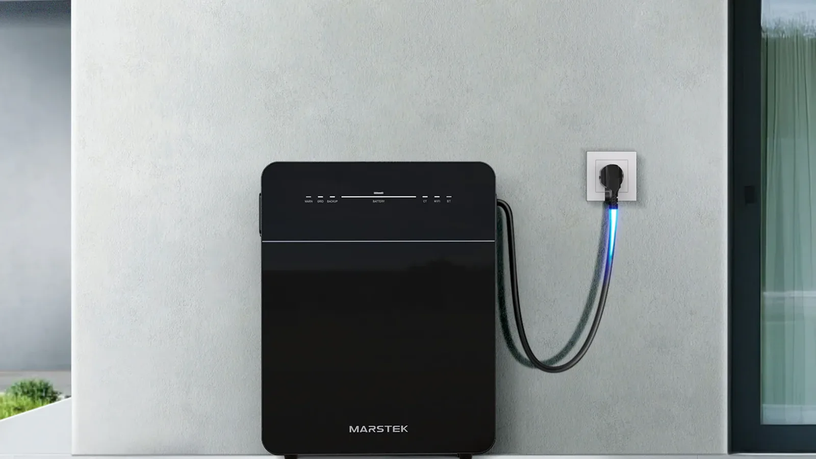 Marstek Venus thuisbatterij buiten tegen een gevel, ingeplugd in een stopcontact naast het raam